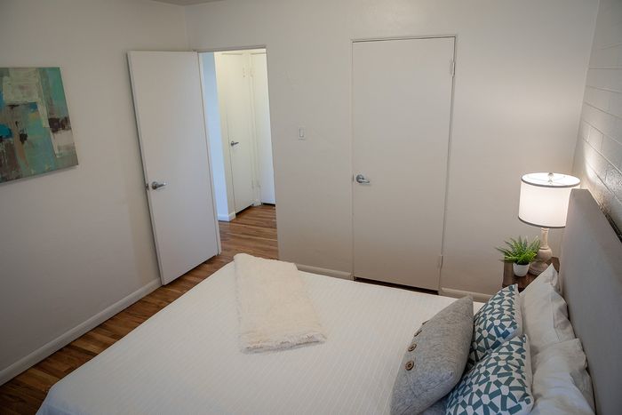 Cozy bedroom with wooden floors, stylish artwork, and ambient lighting for a relaxed atmosphere.