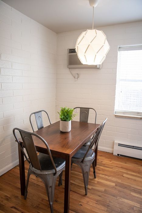 Cozy dining nook featuring a wooden table for four, metal chairs, and a modern geometric pendant light, perfect for intimate meals.