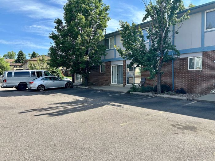Charming apartment exterior surrounded by lush greenery with convenient parking.