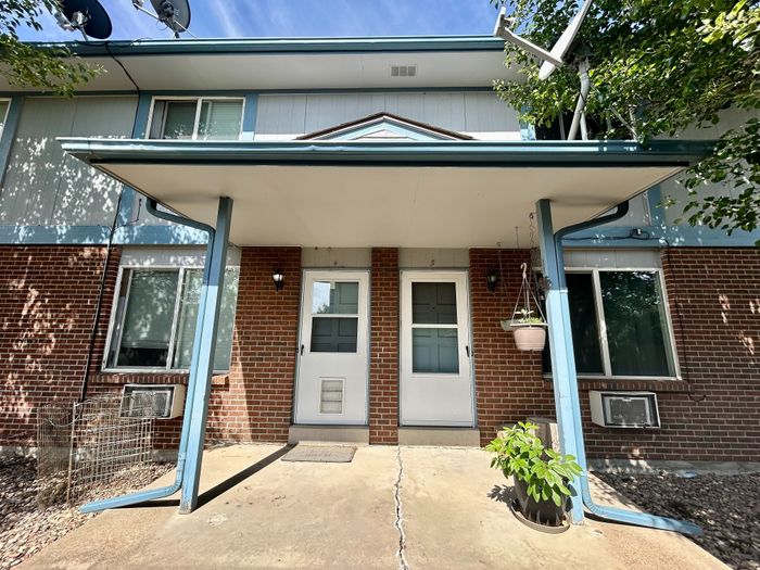 Charming townhouse entrance with a brick facade, elegant blue trim, and inviting porch area.