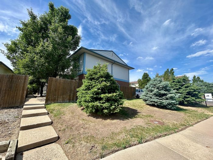 Charming suburban home with lush greenery and a clear blue sky, offering tranquil living in a picturesque neighborhood.