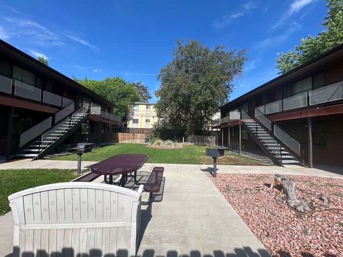 Charming apartment courtyard with modern dual-level buildings, lush green space, and outdoor seating area for relaxed gatherings.