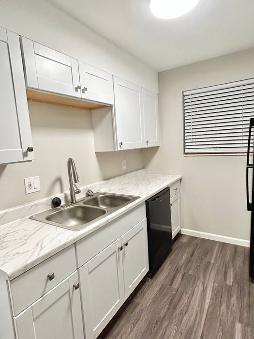 Contemporary kitchen with white cabinetry, marble countertops, and stainless steel sink.