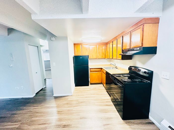 Bright kitchen with wooden cabinets, black appliances, and open layout.