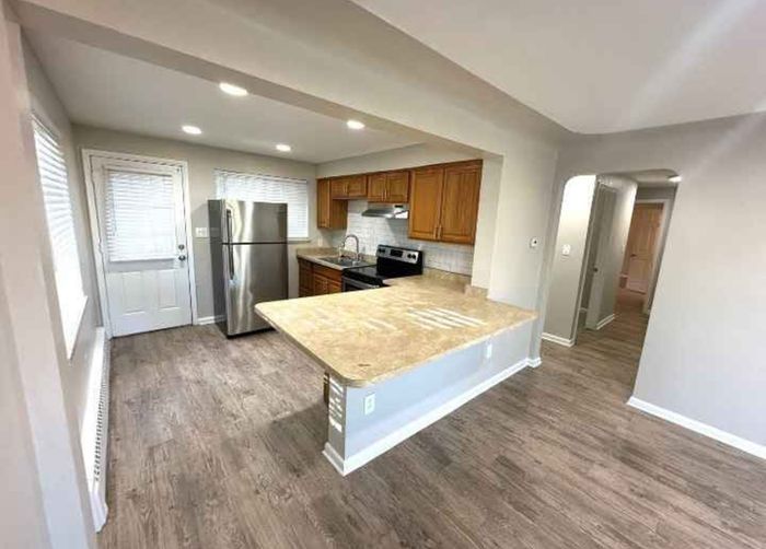 Modern kitchen with wood cabinetry, stainless steel appliances, and light countertops enhancing a spacious layout.