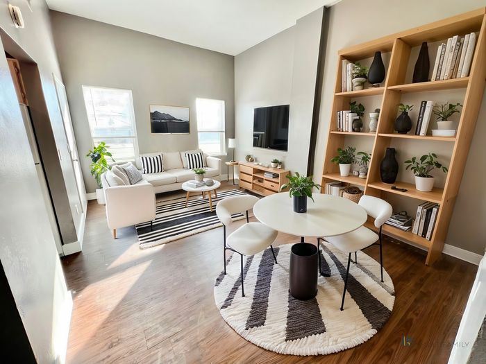 Bright modern living room with cozy seating, chic decor, and a stylish bookshelf, perfect for relaxation.