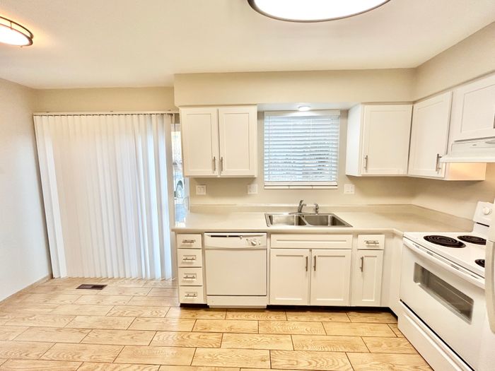 Bright and elegant kitchen with white cabinetry, modern appliances, and hardwood flooring.