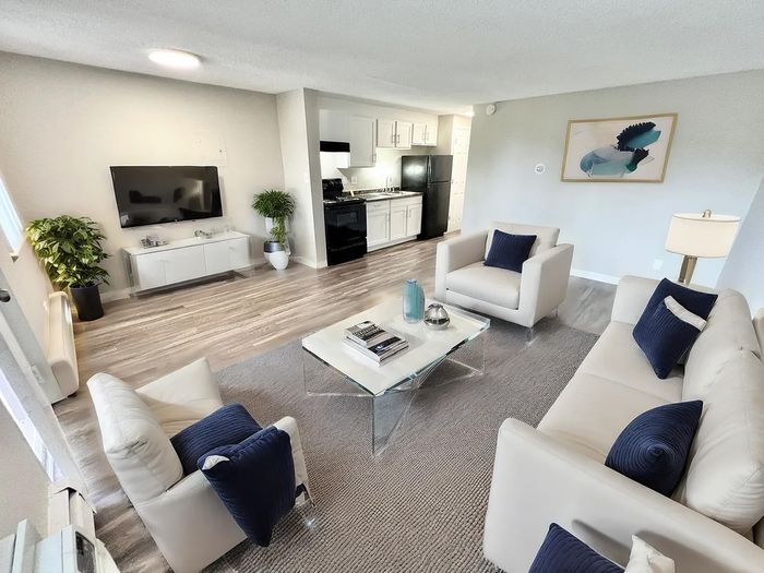 Contemporary living room with sleek white furniture, stylish decor, and an open-plan kitchen, offering a cozy and inviting ambiance.