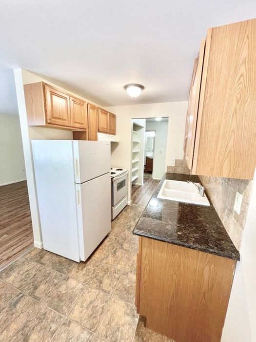 Charming kitchen with granite countertops, wooden cabinets, and modern appliances in a cozy apartment.