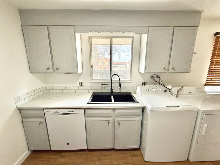 Bright and modern kitchen featuring sleek cabinetry, convenient dishwasher, and an integrated laundry area with washer and dryer.