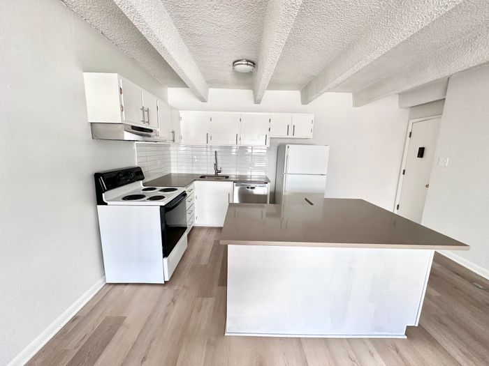 Modern kitchen with sleek white cabinetry, stainless appliances, and spacious island featuring elegant countertops and bright, open layout.
