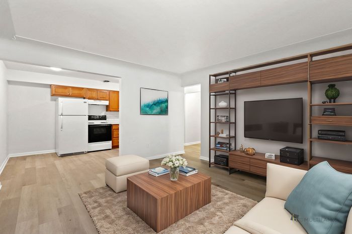 Chic open-plan living space with modern kitchen, cozy living room, and elegant hardwood flooring.