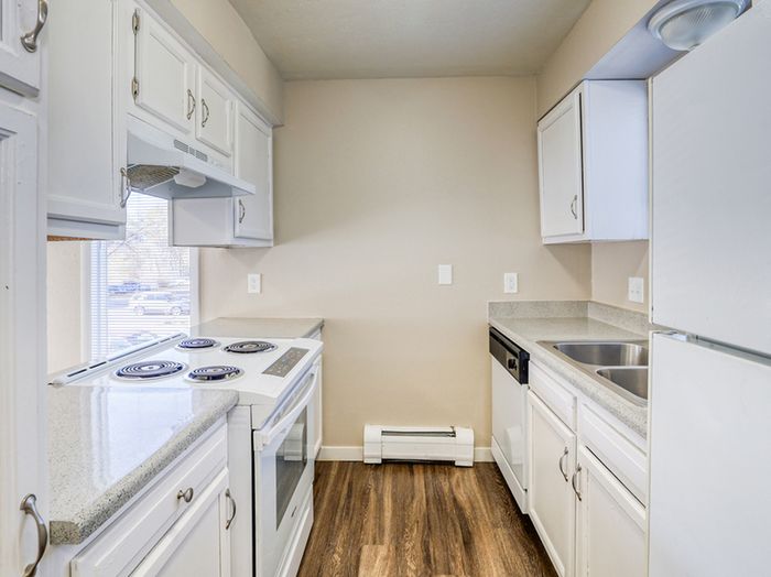 Bright, modern kitchen with white cabinetry, sleek countertops, and hardwood flooring.