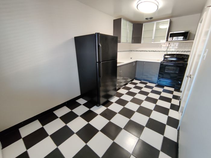 Modern kitchen with sleek black and white checkered flooring, stylish black appliances, and ample cabinet space.