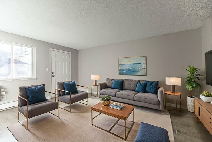 Modern living room with gray sofa, stylish chairs, a cozy rug, and elegant decor in a bright, inviting space.