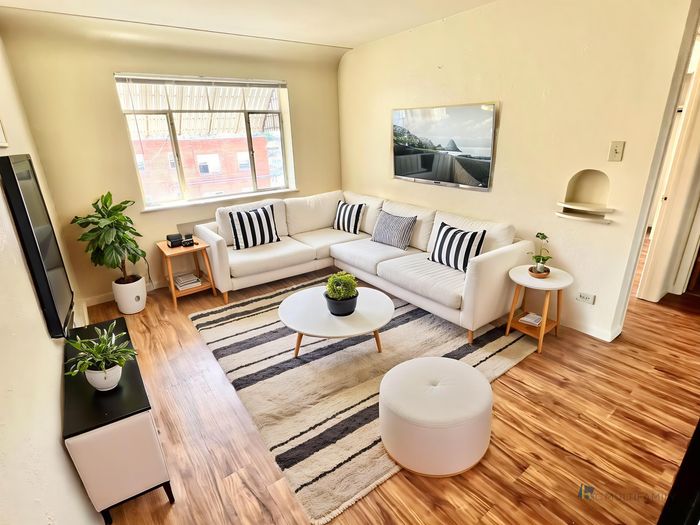 Bright and modern living room with a cozy white sofa, stylish decor, and hardwood floors.