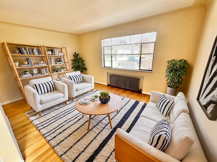 Charming living room with elegant decor, showcasing white furniture, striped cushions, and a cozy ambiance with abundant natural light.