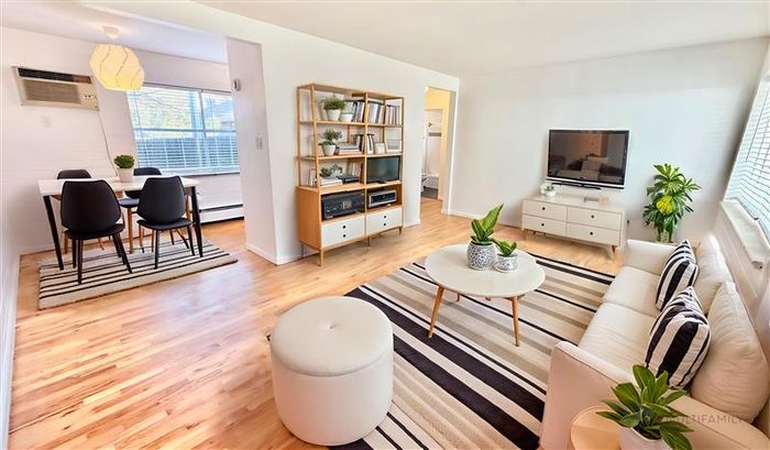 Bright and inviting living room with modern decor, featuring a cozy sitting area, striped rug, and adjacent dining space with natural light.