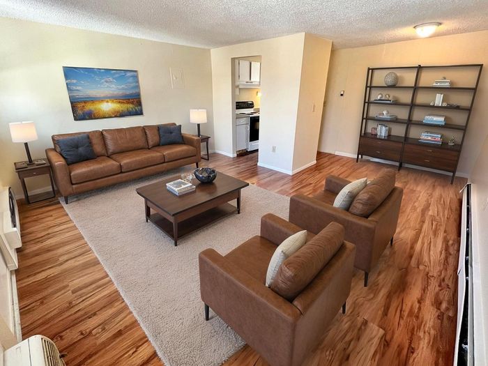 Inviting living room with cozy leather seating, open bookshelf, and warm wood flooring, exuding comfort and style.