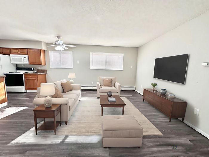 Contemporary open-concept living area with cozy seating, an elegant entertainment center, and a modern kitchen.