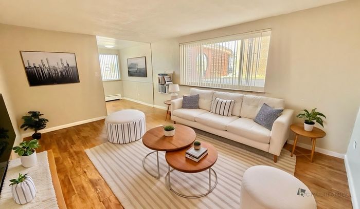 Inviting living room with natural light, featuring a plush sofa, chic tables, and elegant decor.