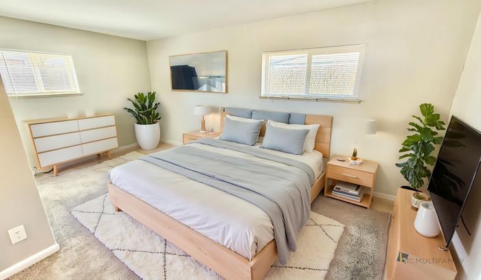 Bright and inviting bedroom with a cozy bed, modern wooden furniture, and vibrant green plants, bathed in natural light.