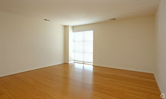 Modern empty living room with natural light and sleek wooden flooring.
