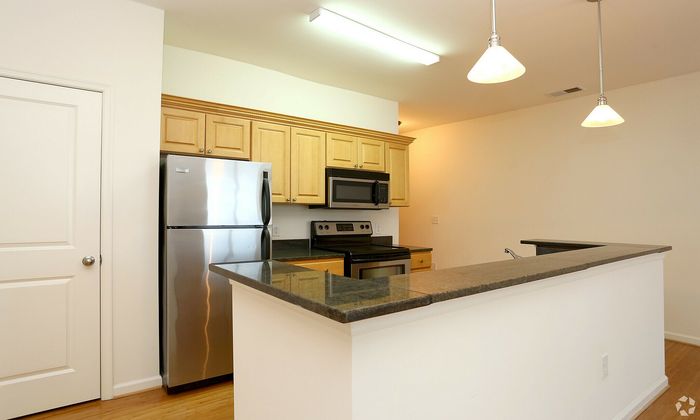 Bright kitchen interior with stainless steel appliances, wooden cabinets, and granite countertops.