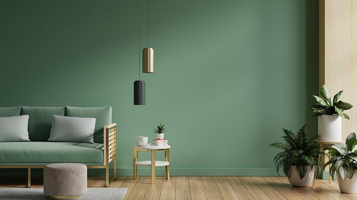 Calm living room with green sofa, modern pendant lights, and lush plants.