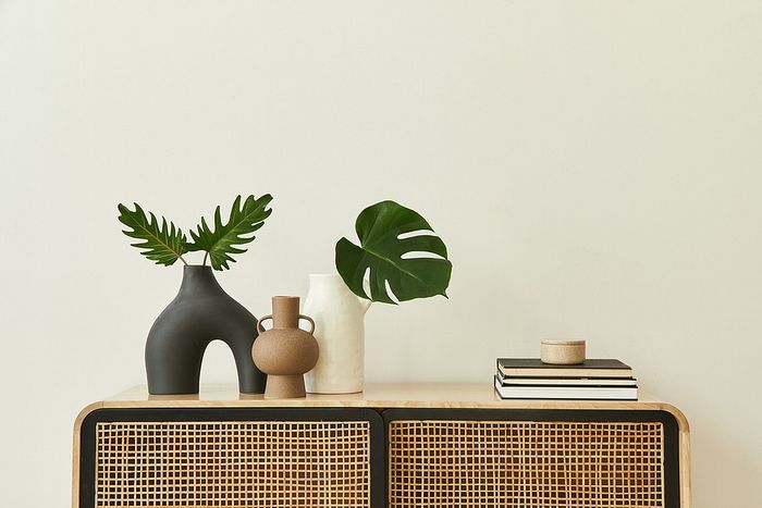 Stylish interior design featuring modern vases and greenery on a rattan console.
