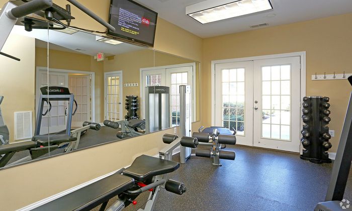 Well-equipped gym room with modern fitness machines and mirrored walls.