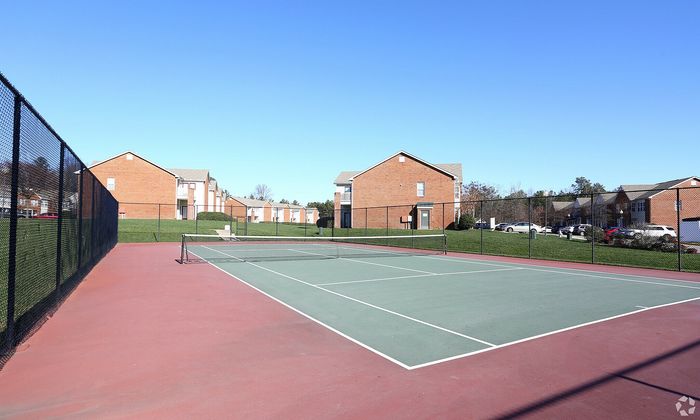 Inviting tennis court surrounded by well-maintained brick apartment buildings in a serene setting.