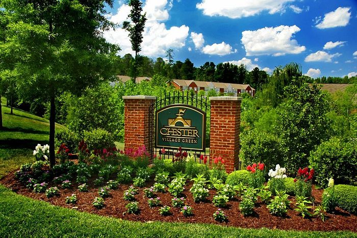 Beautifully landscaped entrance to Chester Village Green with vibrant flowers and a welcoming sign.