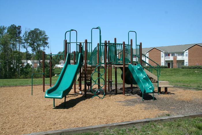 Inviting playground with green slides and climbing structures set in a sunny residential area.