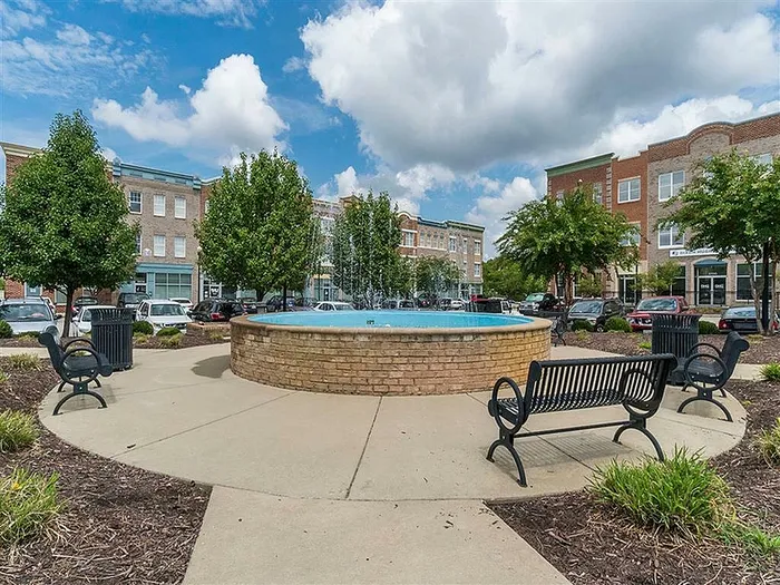 Inviting town center courtyard with a central fountain, surrounded by brick buildings and lush greenery.