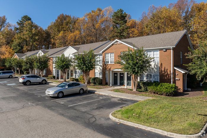 Attractive brick apartment buildings with welcoming entrances and lush trees in a serene neighborhood.