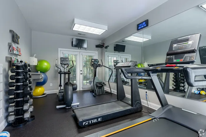 Modern gym room with treadmills, stationary bikes, and exercise equipment.