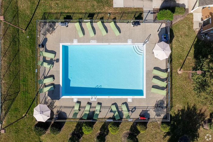 Aerial view of a pristine swimming pool surrounded by green lounge chairs and patio umbrellas.