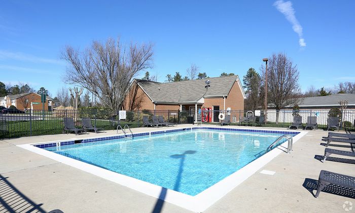 Vibrant swimming pool with lounge chairs set against a clear blue sky and a charming clubhouse.