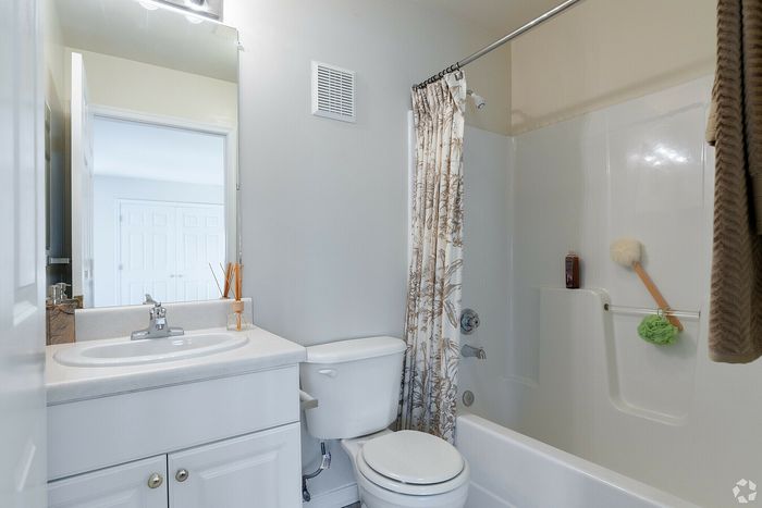 Modern bathroom with elegant fixtures, featuring a sink, toilet, and shower with stylish curtain.