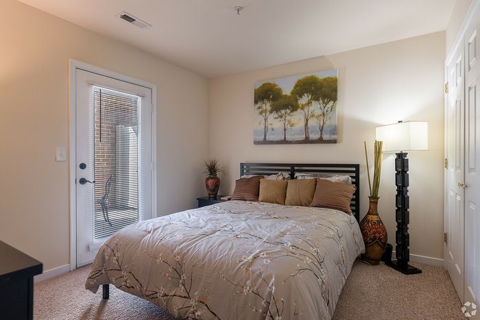Cozy bedroom with stylish decor, featuring a tree artwork, soft lighting, and patio access.