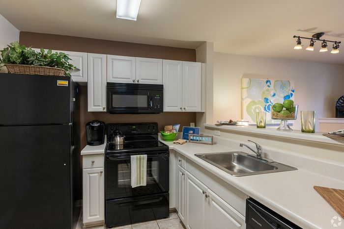 Contemporary kitchen showcasing sleek black appliances, white cabinetry, and elegant lighting.