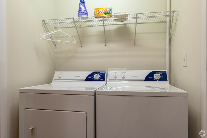 Cozy laundry area with modern washer, dryer, and storage shelf.