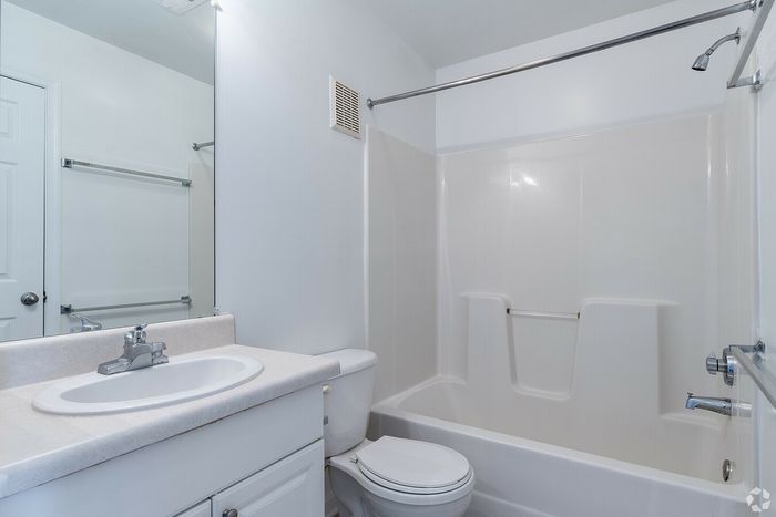 Bright and modern bathroom with white fixtures, featuring a sleek vanity and a bathtub-shower combo.