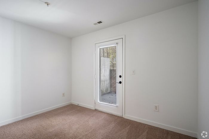 Inviting room with plush carpet and a glass door leading to an outdoor space.