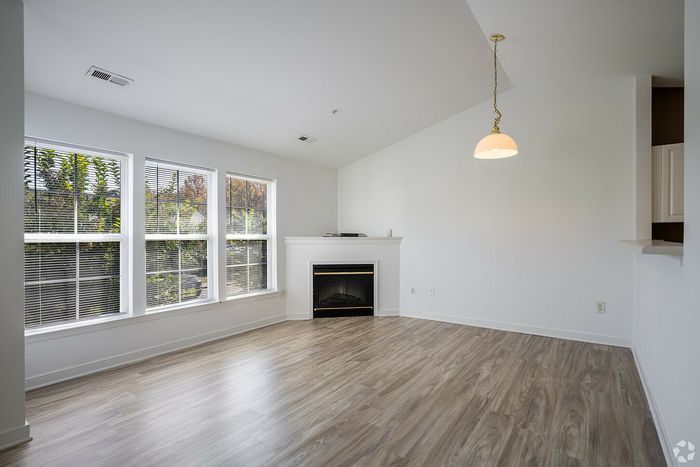 Spacious living room with large windows, natural light, hardwood floors, and a cozy fireplace.