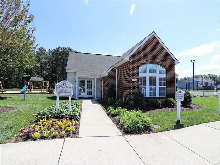 Inviting leasing office with red brick exterior and vibrant landscaping.