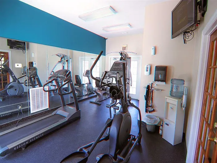 Bright fitness room featuring modern exercise equipment and a mirrored wall for an enhanced workout experience.