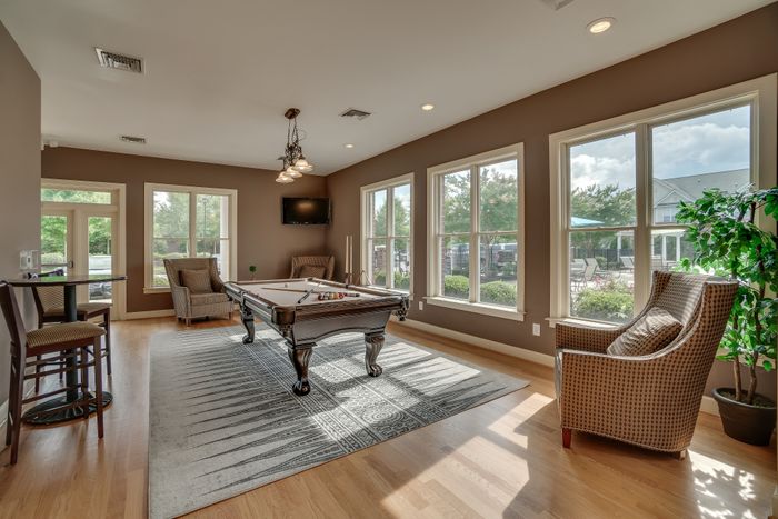 Bright lounge area featuring a pool table, stylish seating, and large windows with garden views.