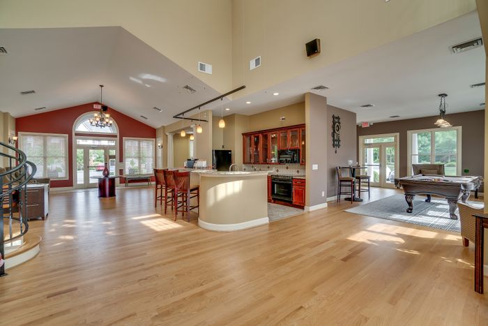 Spacious open living area with hardwood floors, a modern kitchen, and large windows providing natural light.
